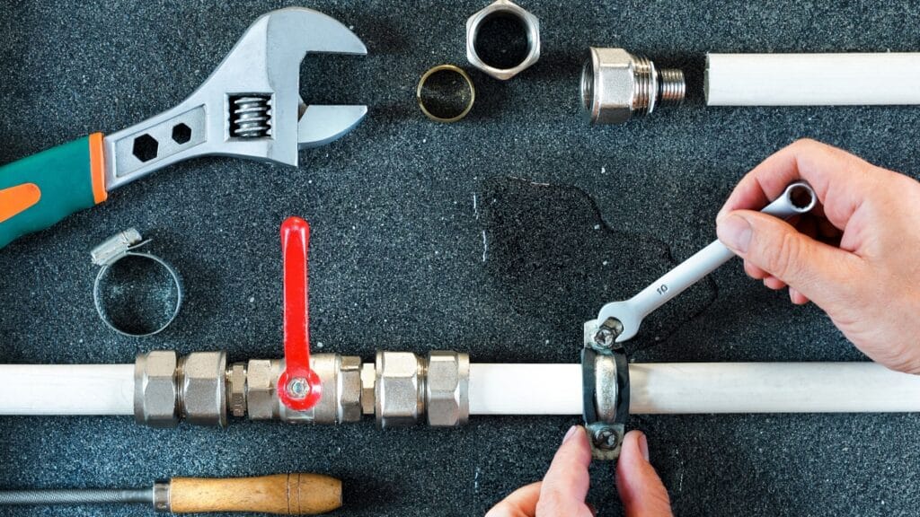 Plumber repairing a pipe valve with an adjustable wrench in Zephyrhills