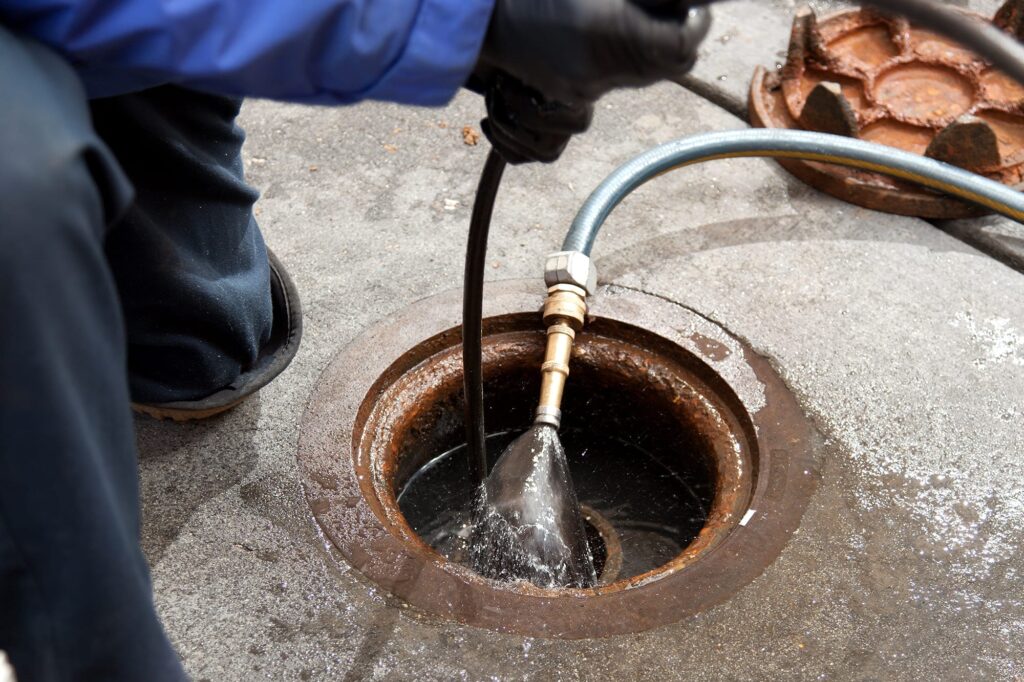 Plumber hydro jetting a sewer line through a manhole in Zephyrhills
