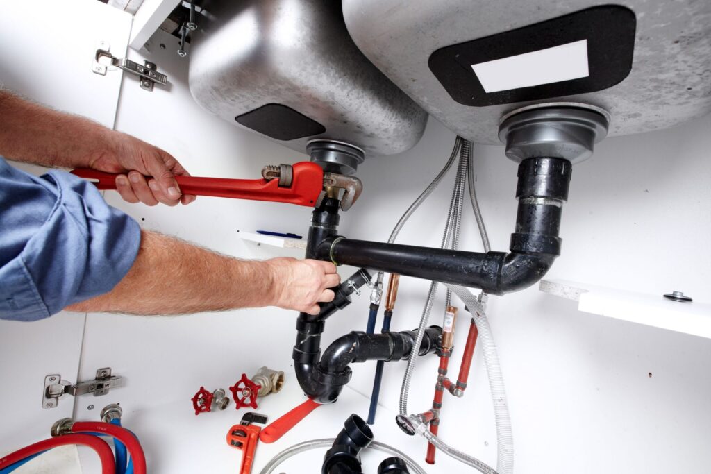 Plumber repairing drain pipes beneath a kitchen sink in Zephyrhills