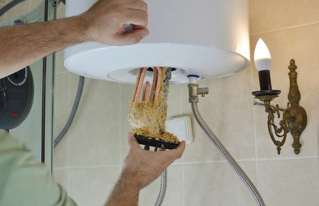 Technician removing mineral buildup from a water heater in Zephyrhills