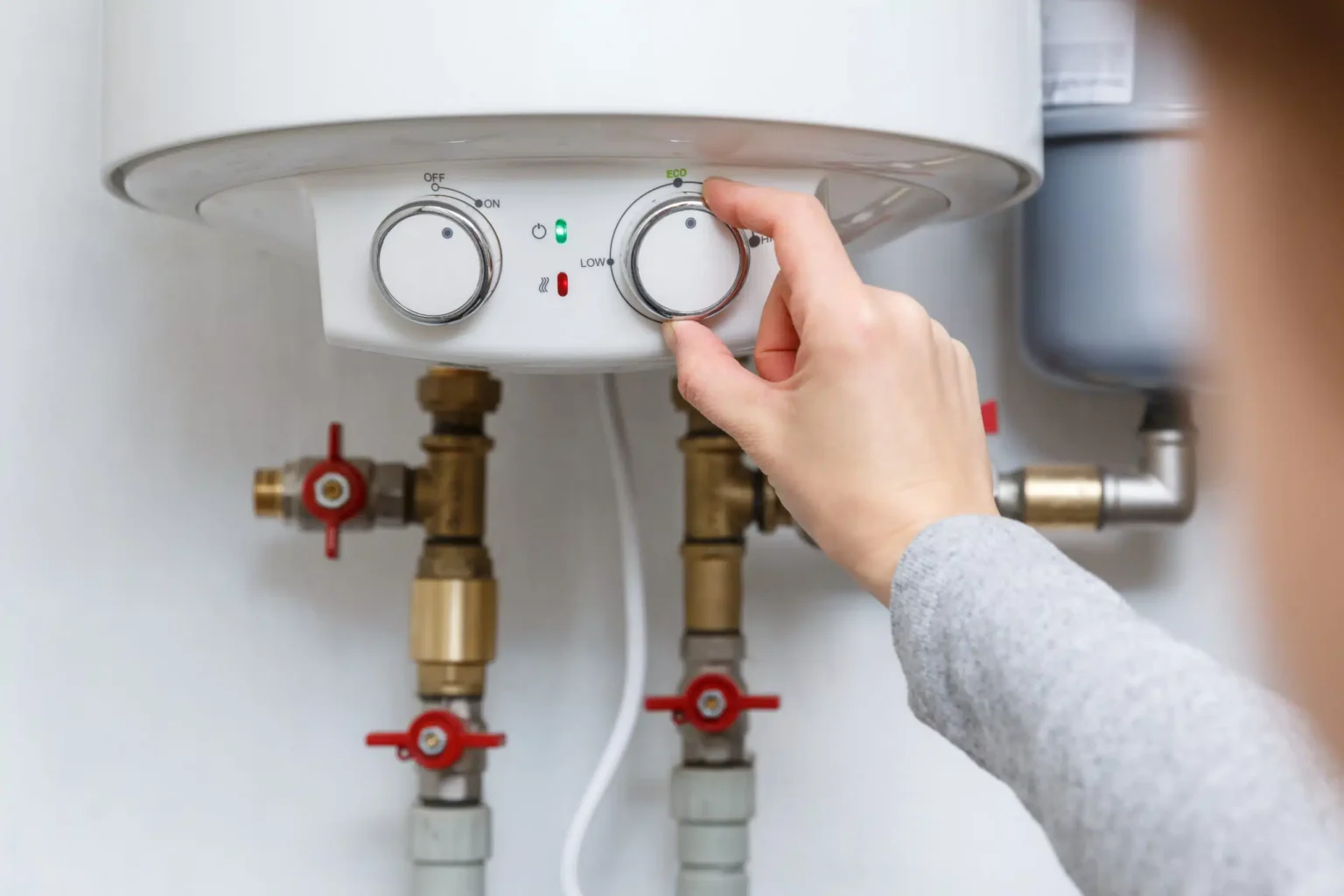 Homeowner adjusting the temperature controls on a water heater in Zephyrhills